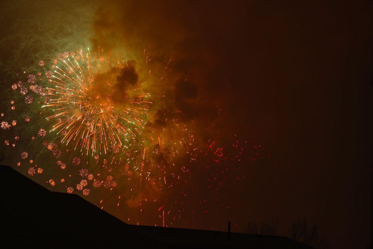 Golden fireworks bursting against dark night sky.