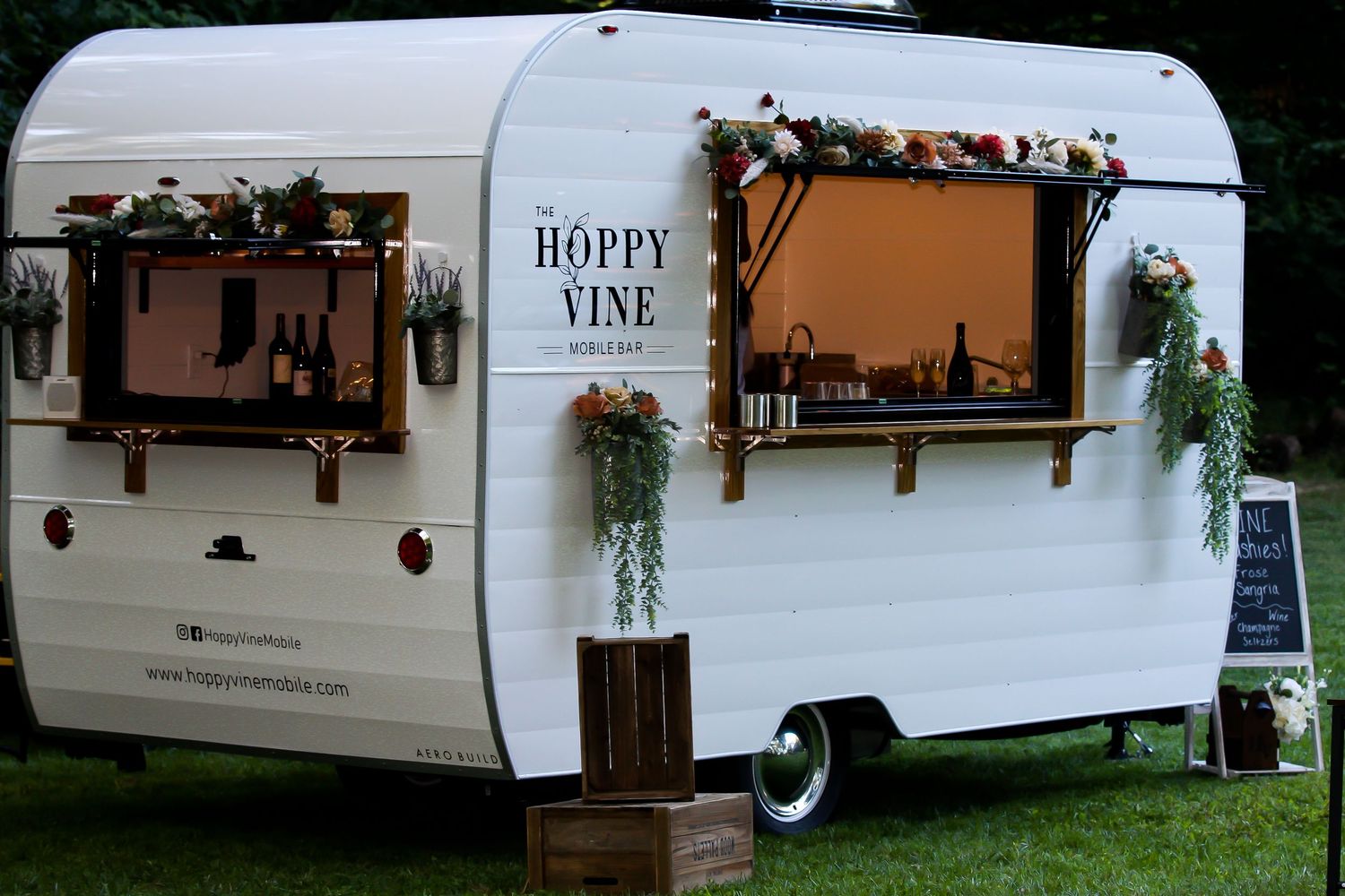 Row of vintage white camper trailers decorated with flower boxes and rustic accents.