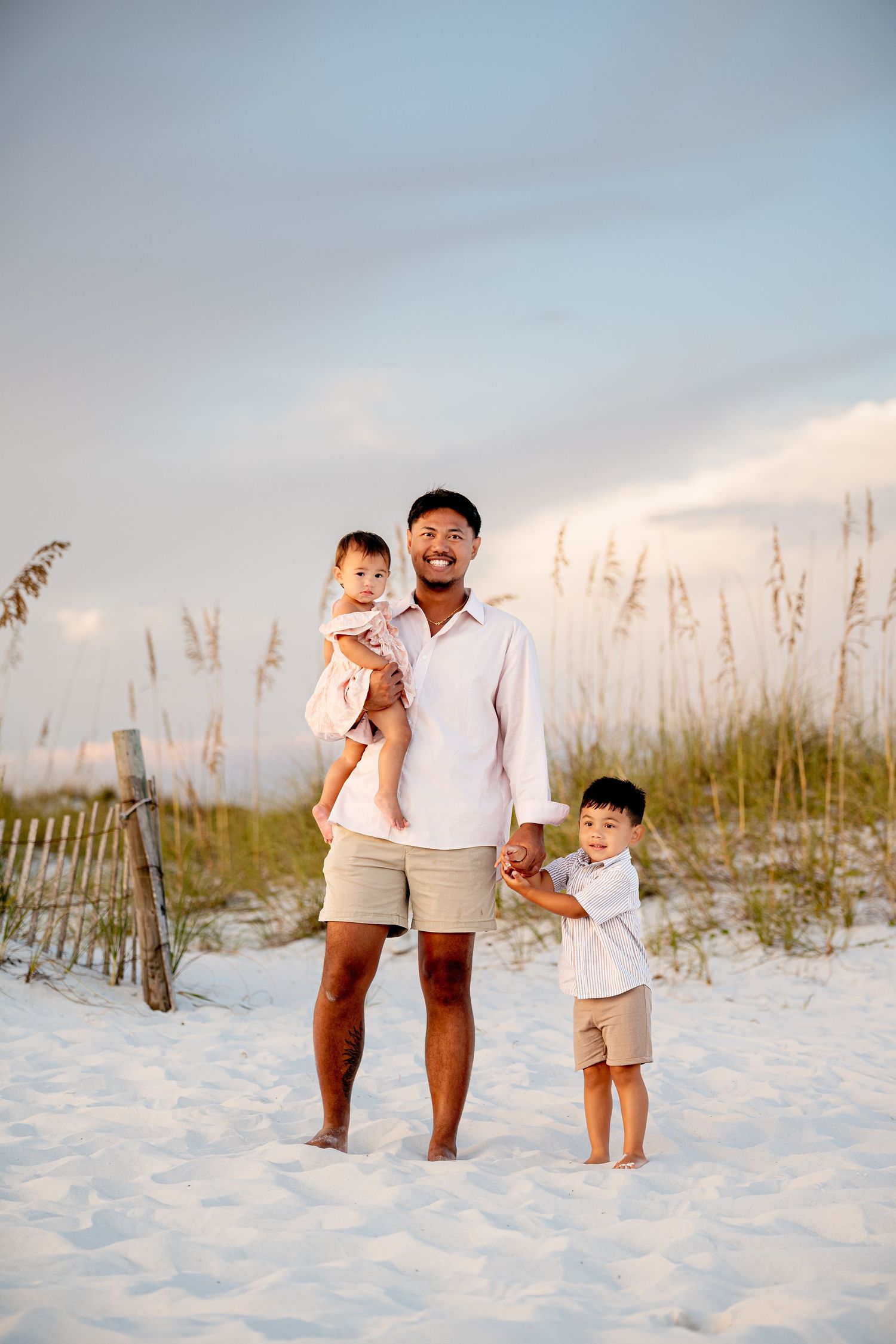 A family enjoys a sunset walk together on a white sandy beach with sea oats in the background. family friendly things to do while visiting
