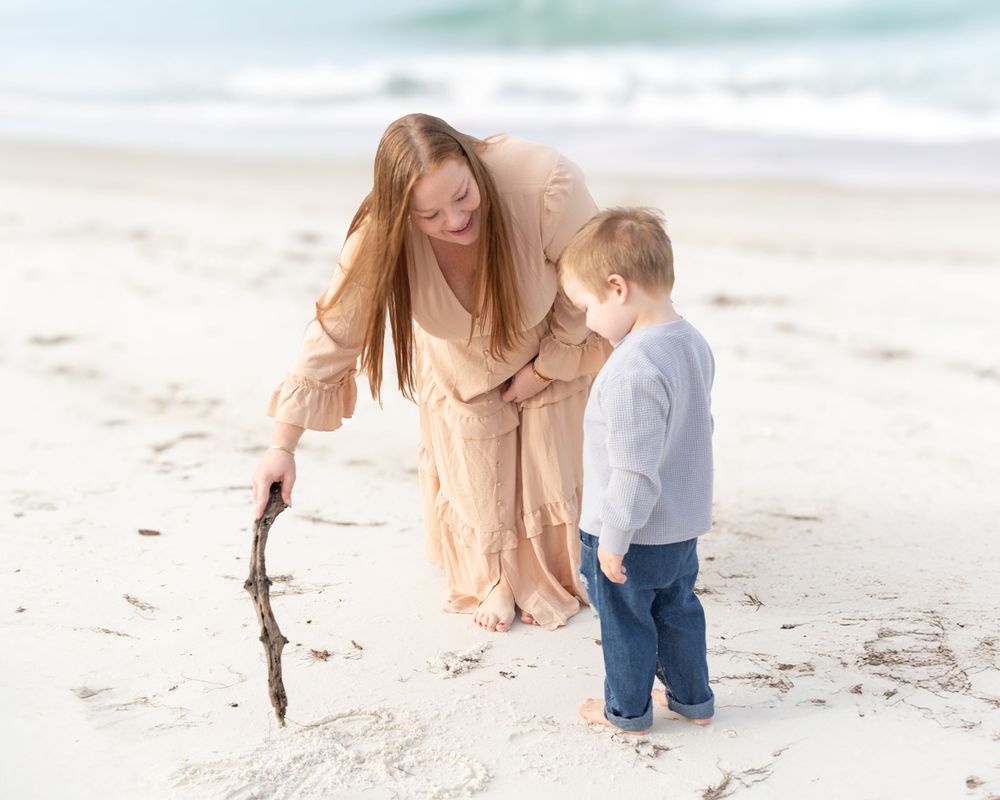 Family enjoying a playful moment together while walking on a sunny beach with palm trees in the background.
