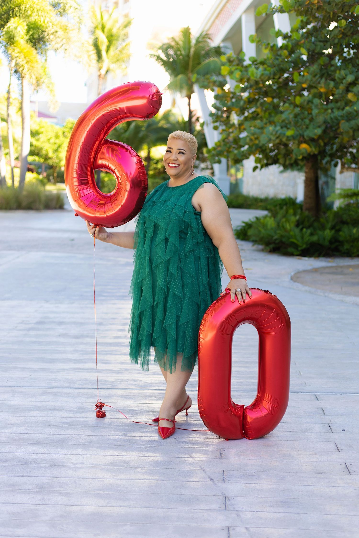 Green dress and red number balloons create a festive outdoor photo shoot scene.