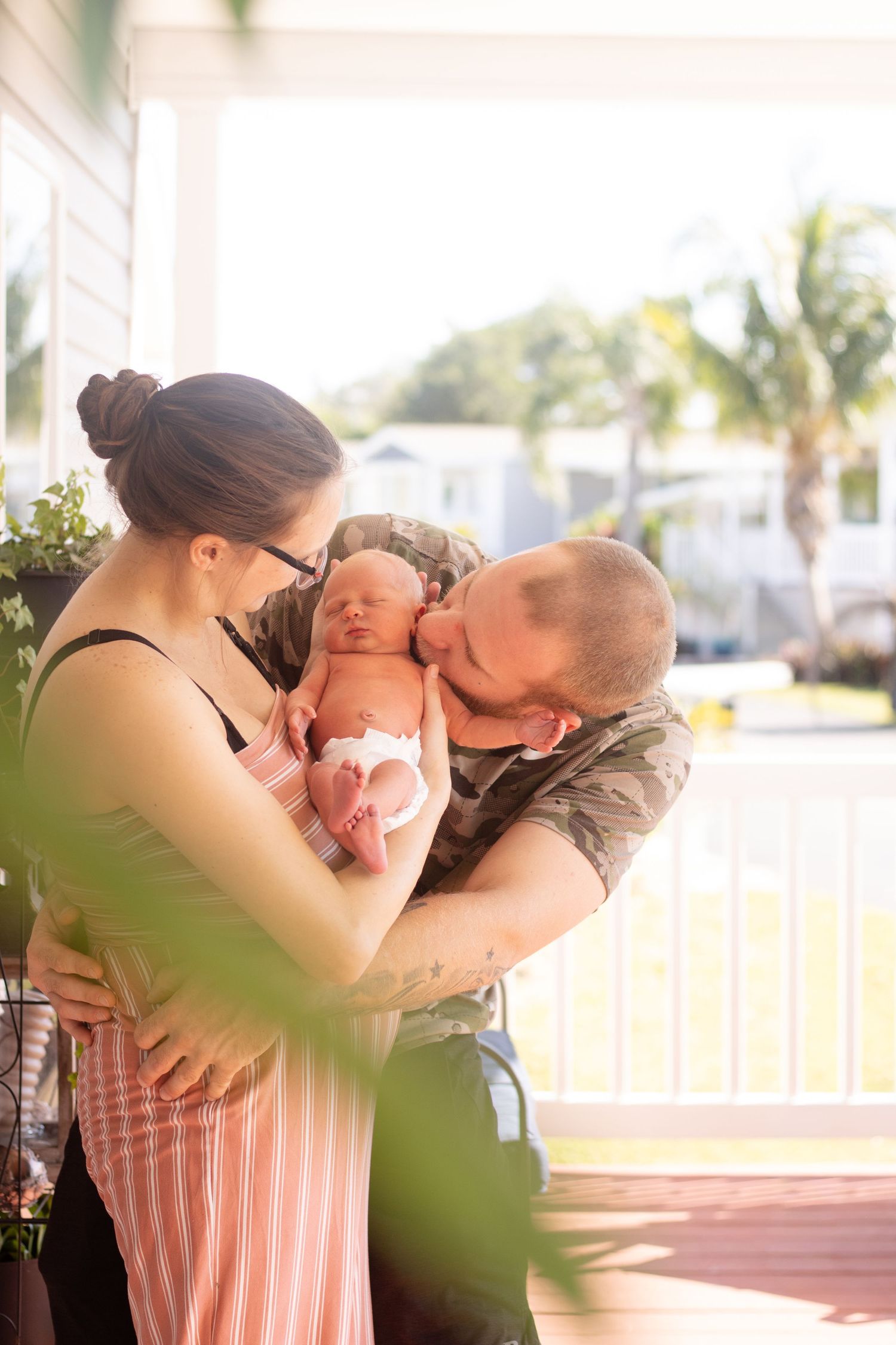 dad kissing newborn baby outside