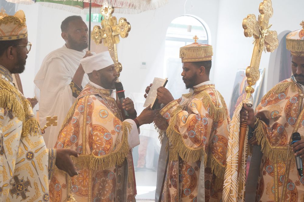 Ethiopian Orthodox priests in golden robes reading from sacred text during religious ceremony.