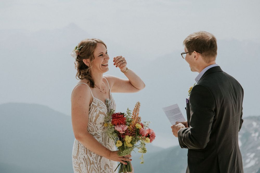 A joyful wedding moment captured on a snowy mountain summit with stunning alpine views.