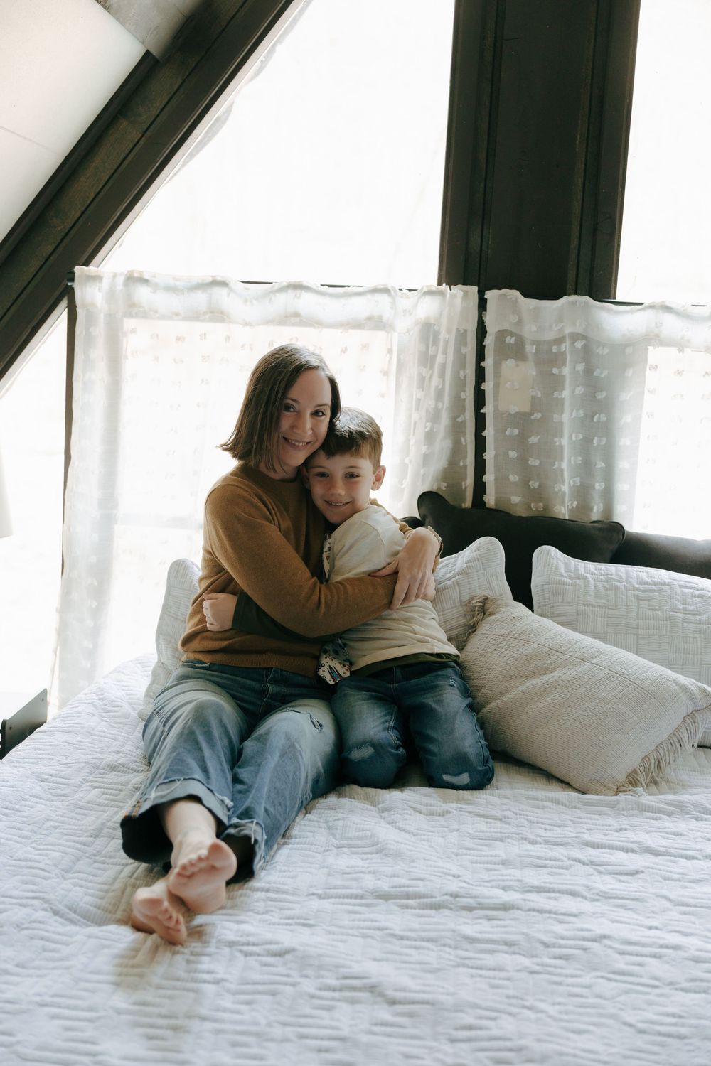A tender moment captured in black and white as two people embrace while relaxing together on a white bed.
