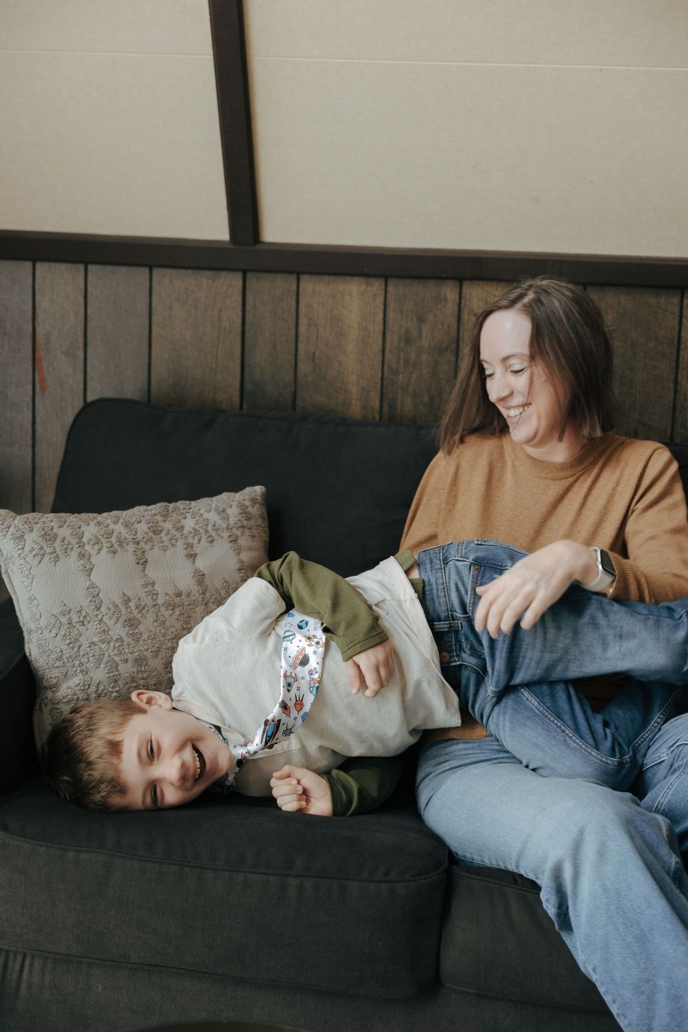 A candid series of photos showing someone lounging and relaxing on a dark gray couch in casual attire.
