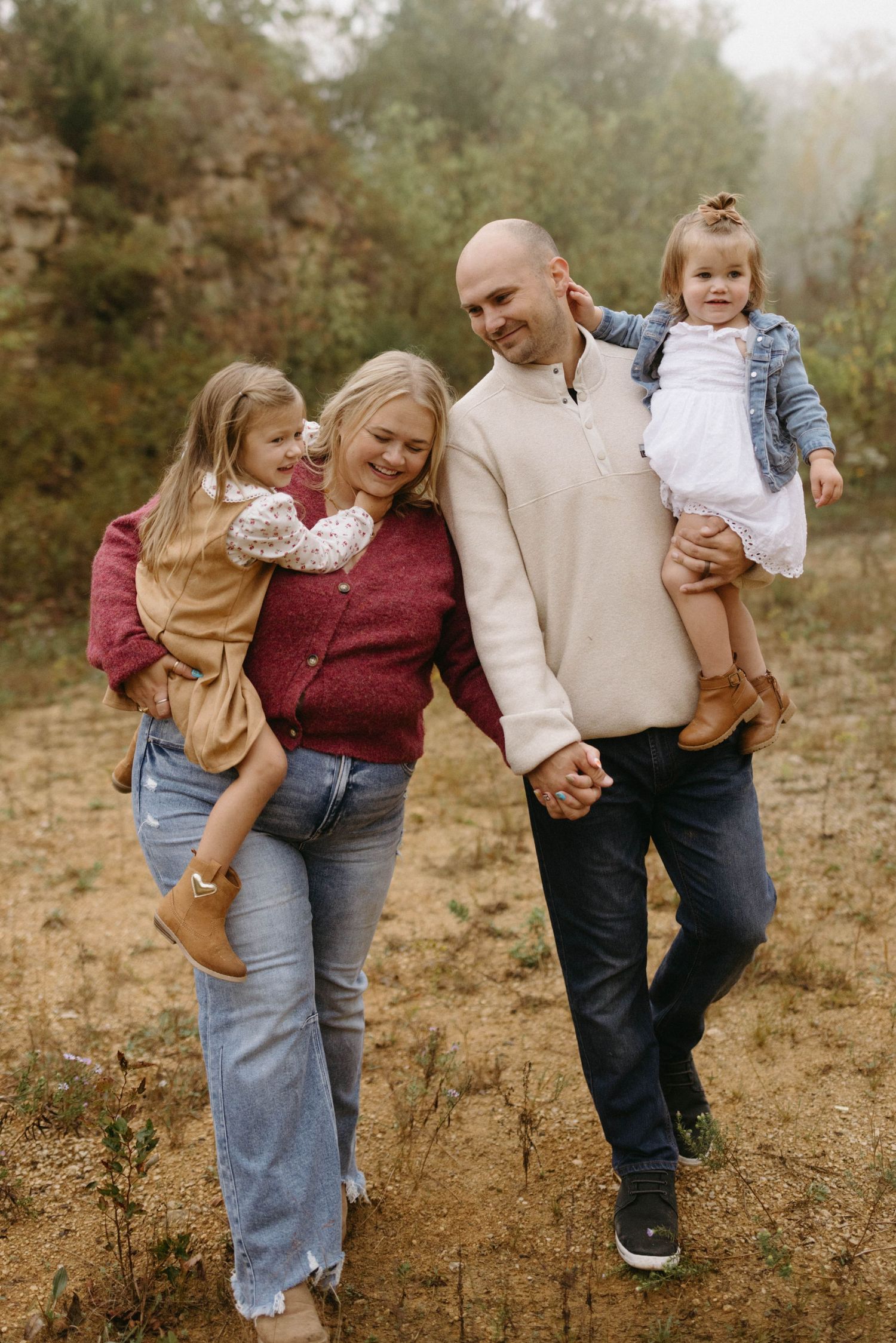 A family wearing casual denim and earth tones poses together outdoors in a natural autumn setting.