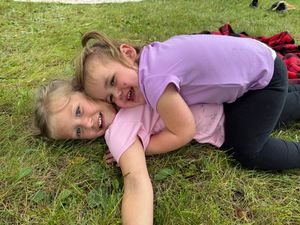 A series of six connected photos showing someone lying and rolling on green grass in a playful manner.