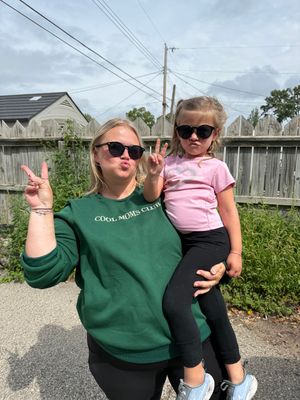 A series of candid photos showing a person in a green sweatshirt holding a small child in pink outdoors.