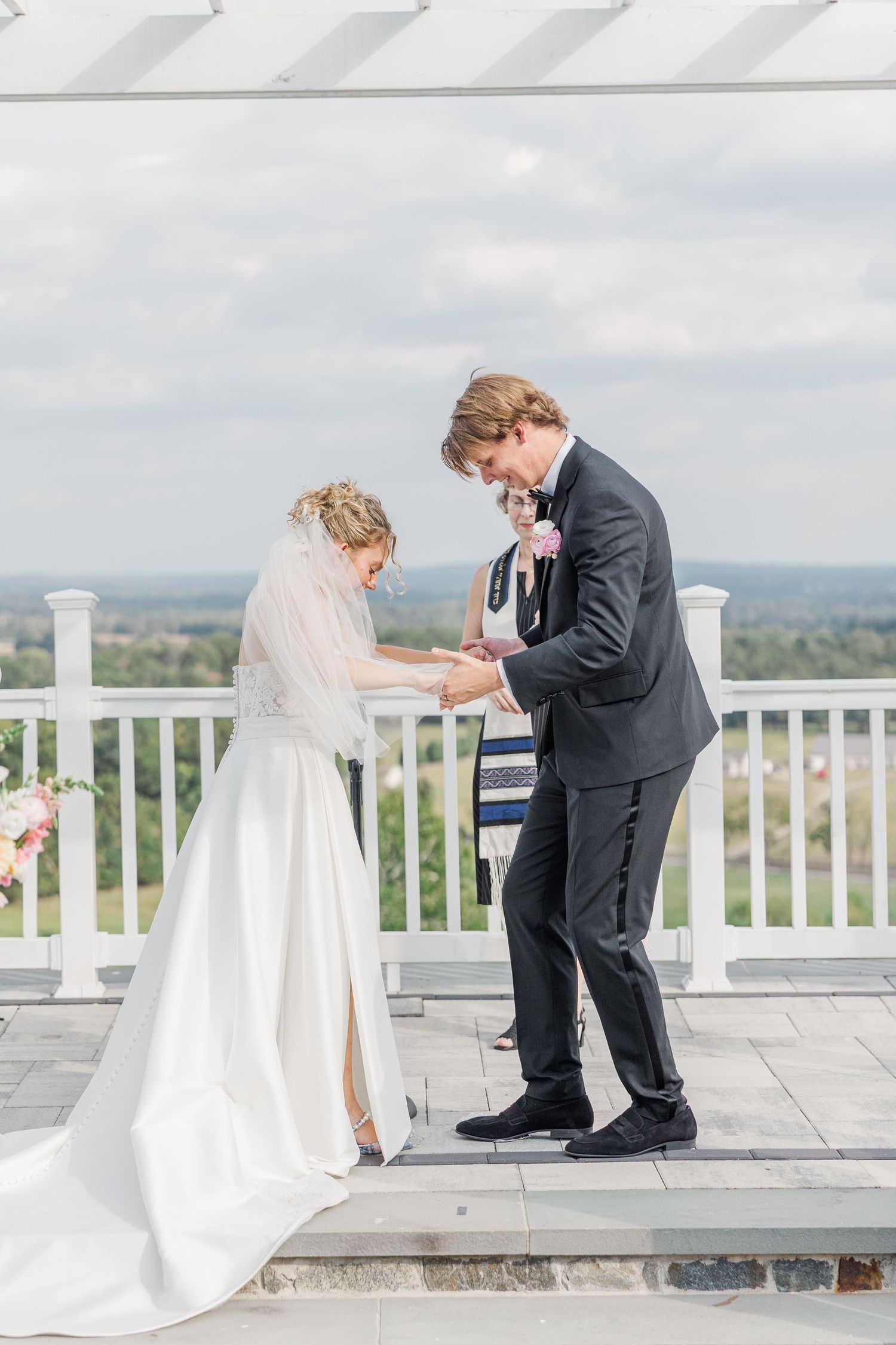 Emotional wedding ceremony moment captured on an elegant white terrace with scenic mountain backdrop.