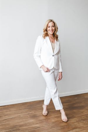 Professional fashion photo series showing a white pantsuit outfit against a minimalist studio backdrop with wood flooring.