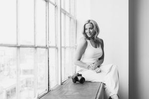 Black and white portraits by a window showing someone in casual white attire in relaxed seated poses.