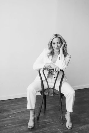 Black and white fashion photo series showing a person in a white suit posing with a chair on wooden floor.