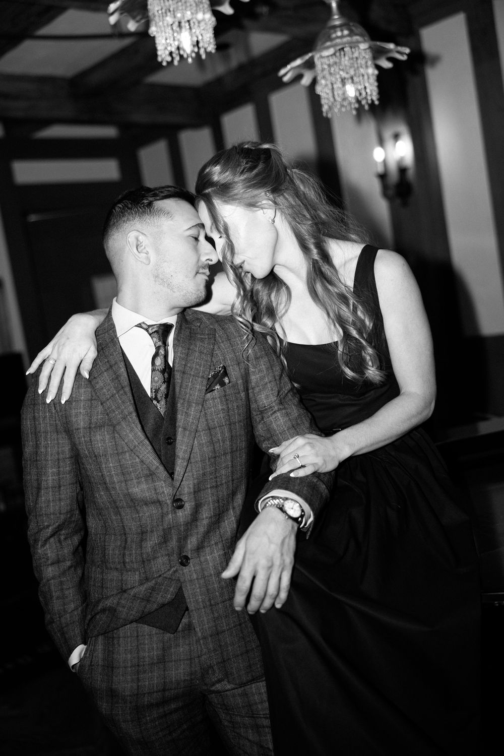 A couple shares an intimate dance moment under crystal chandeliers in a black and white photo series.