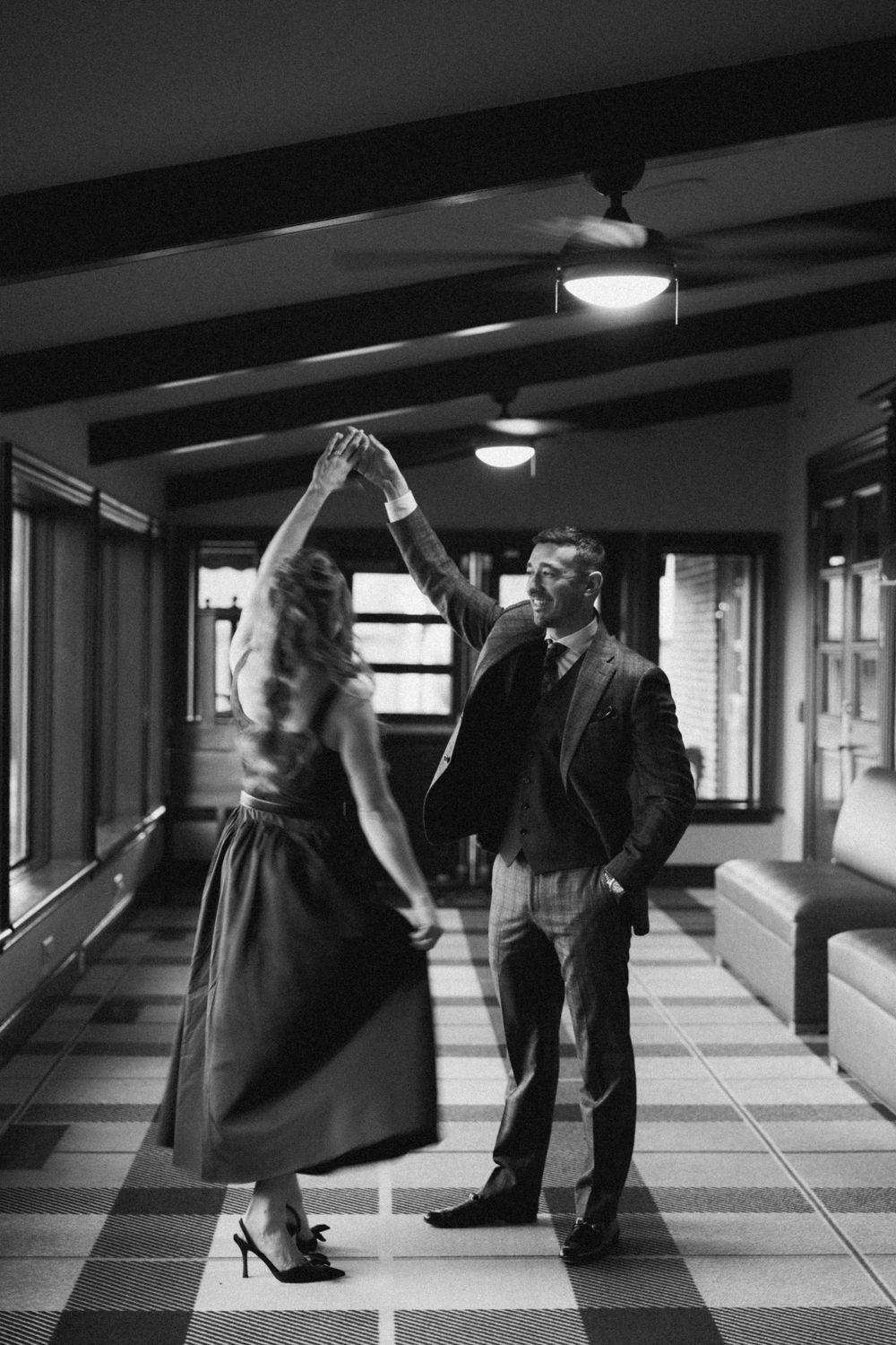 A couple performs a romantic dance sequence in a monochrome hallway setting.
