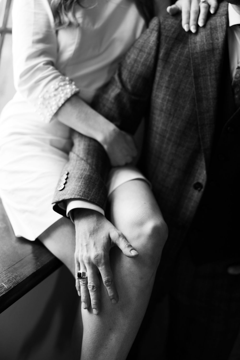 Black and white close-up of formal attire showing suit sleeve details and jewelry.