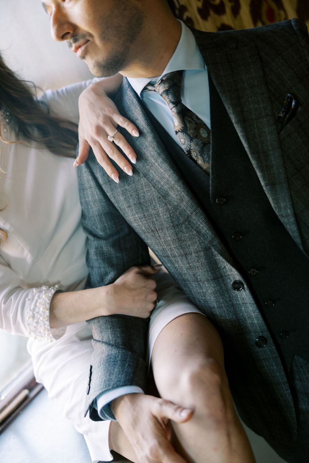 Close-up shots of couple in formal wear sharing intimate moments on white furniture.