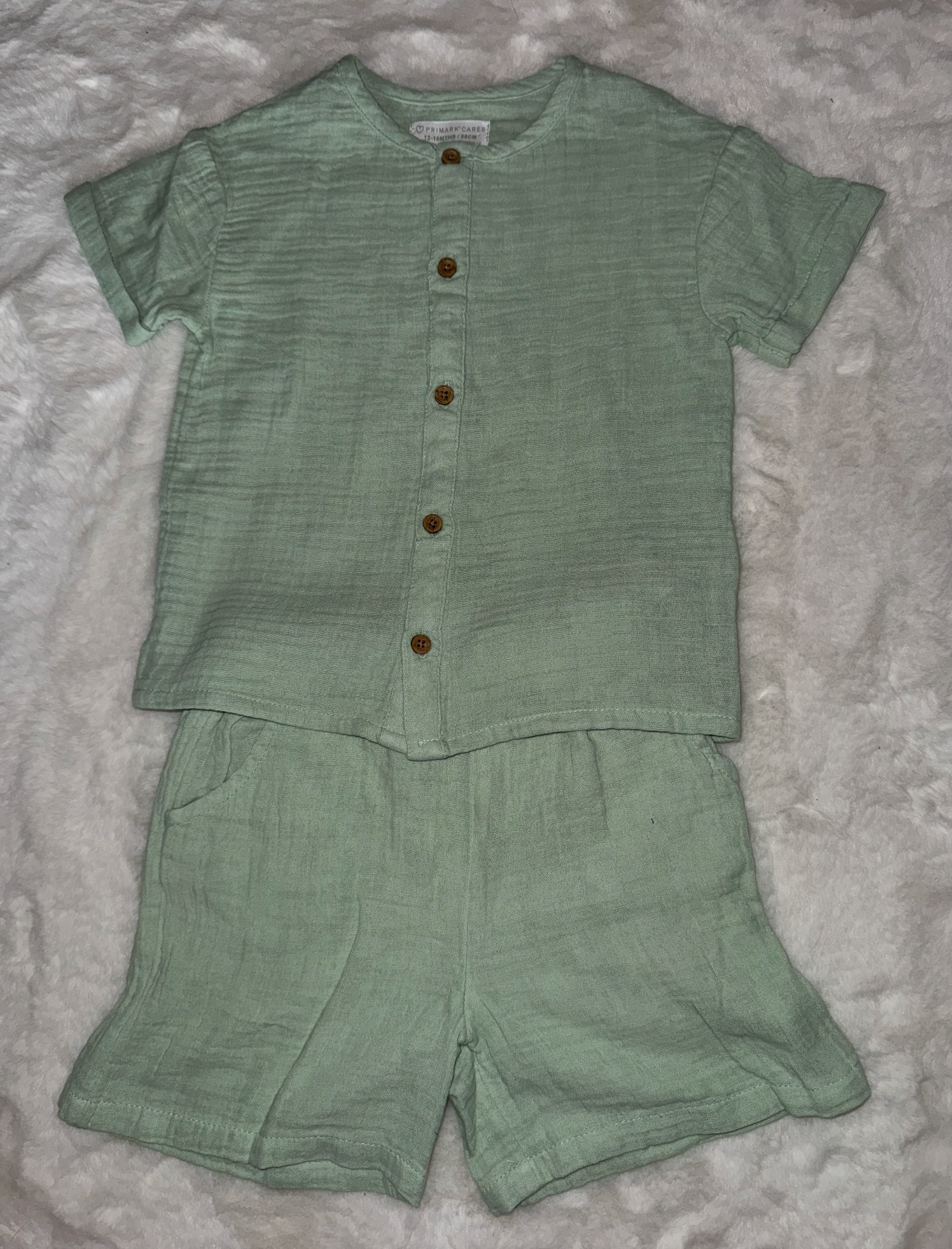 Sage green linen baby romper set with buttons and short sleeves shown from different angles.
