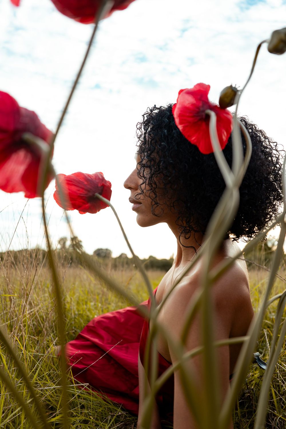 A dreamy portrait among vibrant red poppies in a summer field.