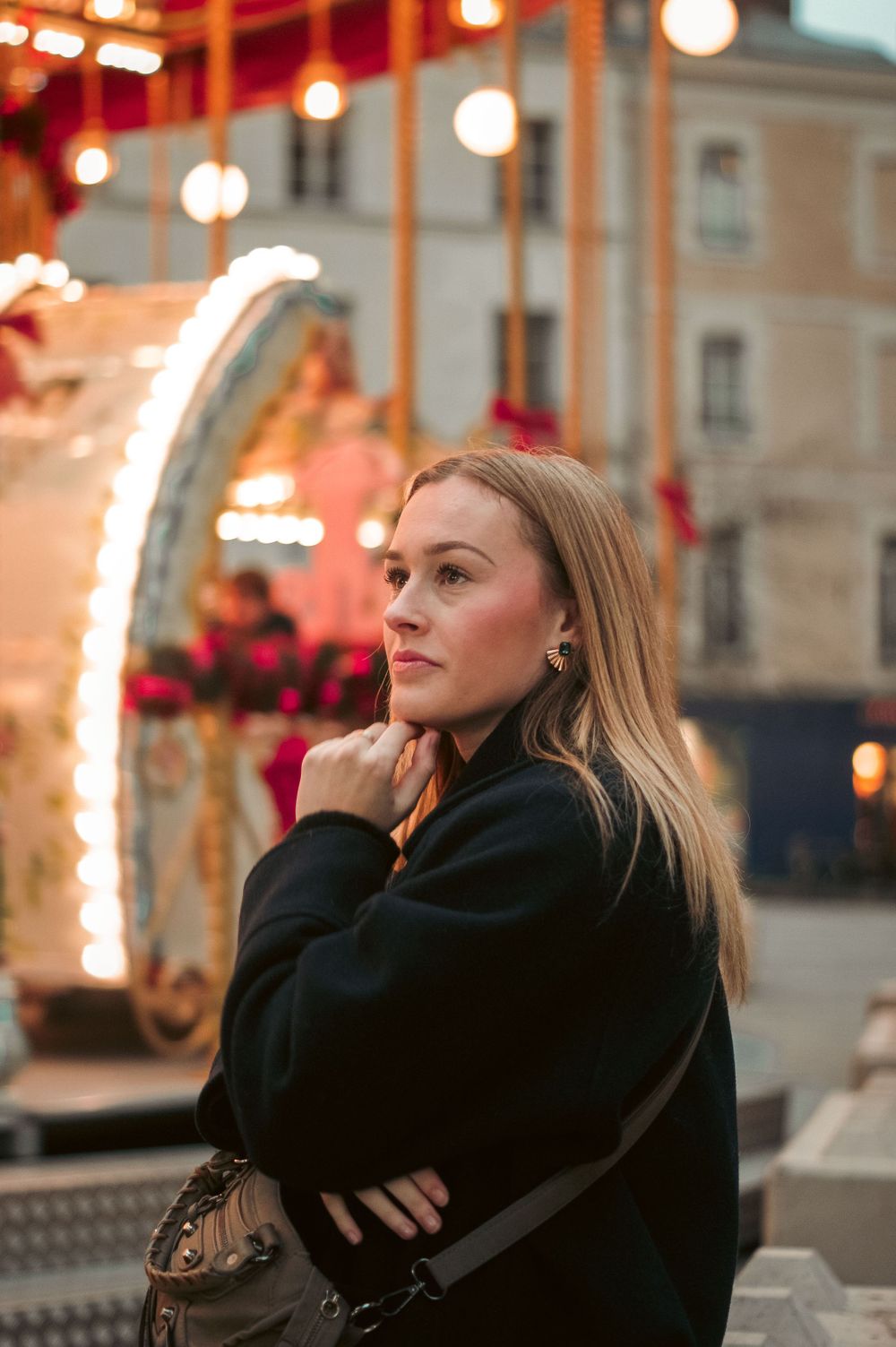 An evening portrait with carnival lights and architecture in the background.