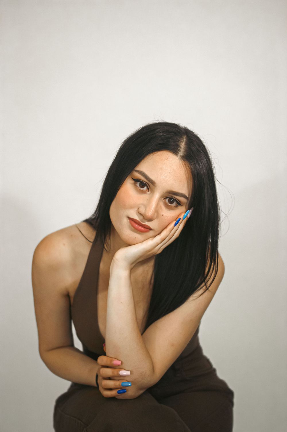 A minimalist studio portrait with soft lighting and blue nail polish.
