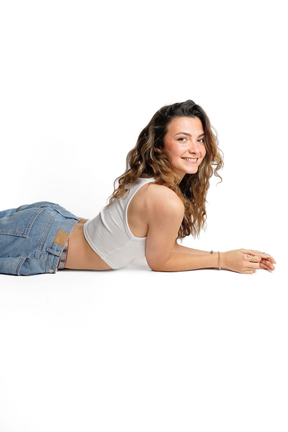 Relaxed studio portrait of person lying down in casual denim and white tank top.