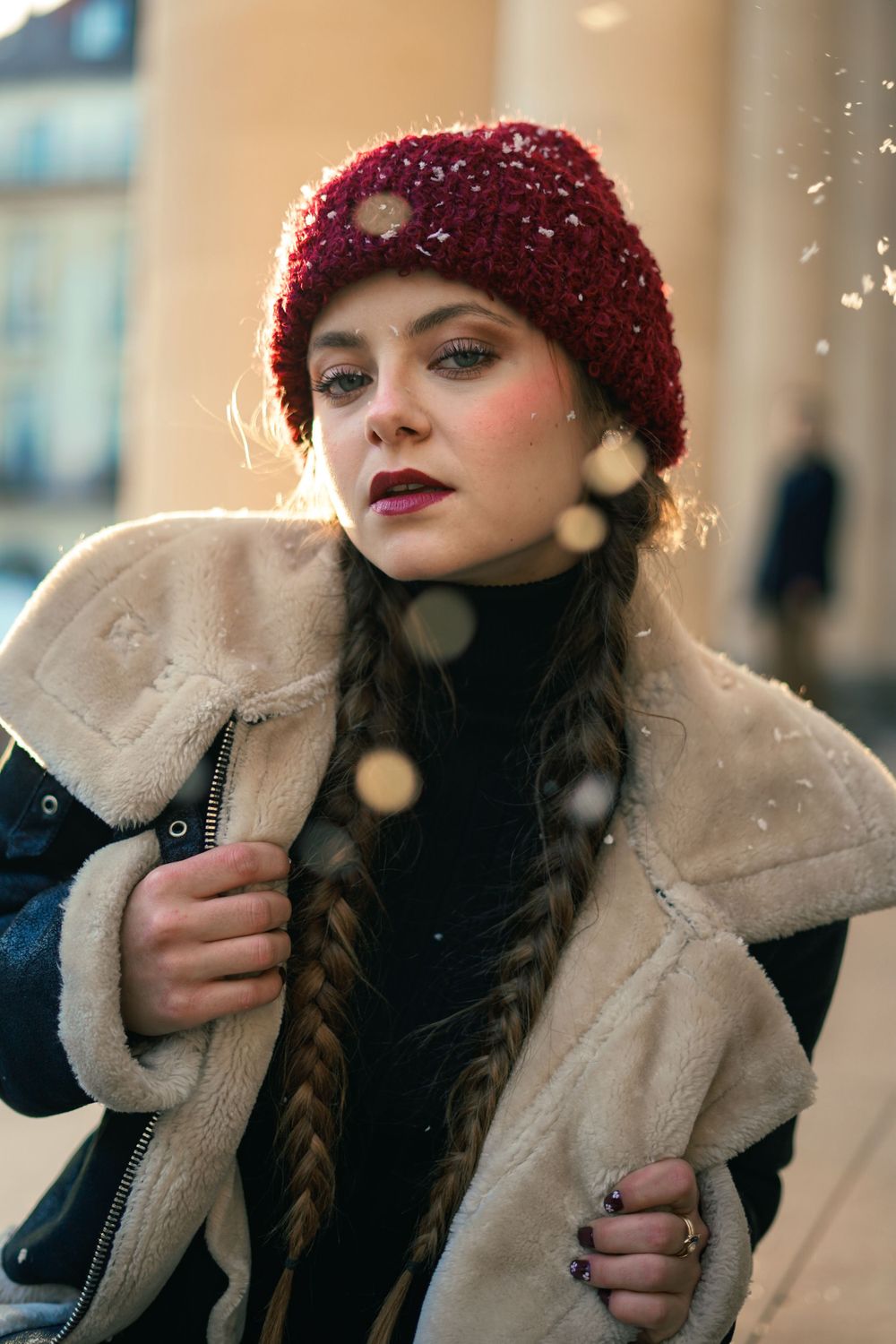 A winter fashion portrait with burgundy beanie and snowflake bokeh effects.