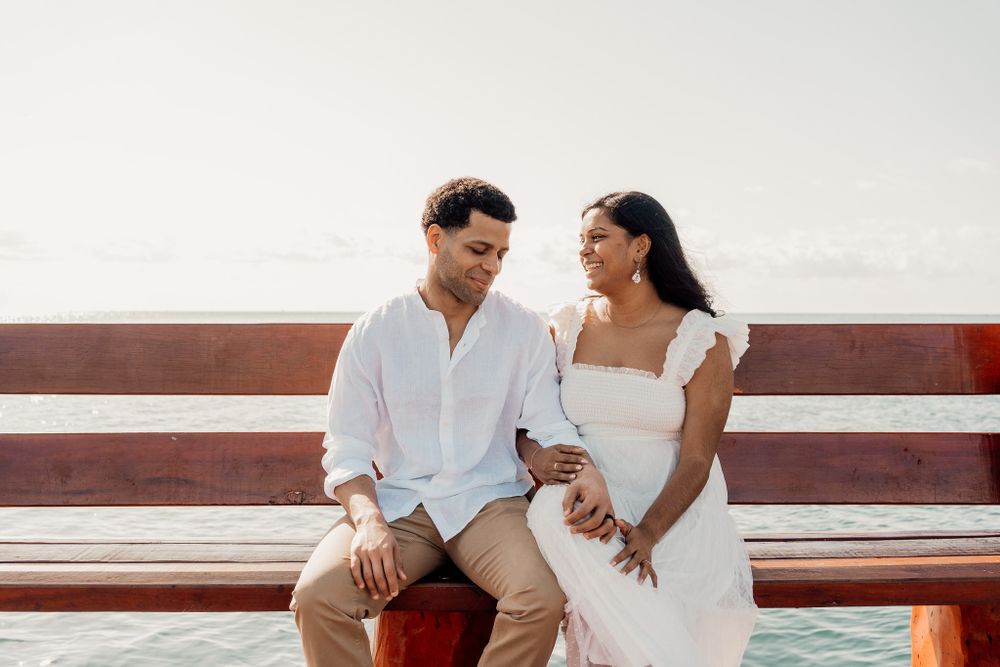 Romantic couple in white clothing sitting together on wooden pier by the ocean photoshoot in Puerto Morelos.