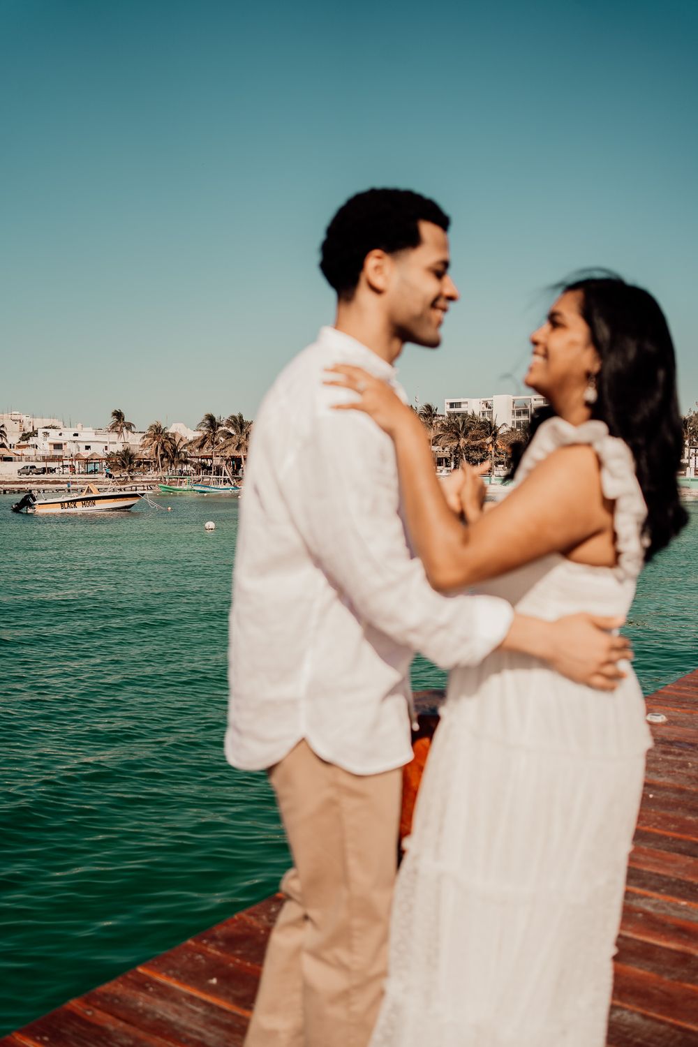 Couple dancing on wooden dock with turquoise ocean waters in background photoshoot in Puerto Morelos.