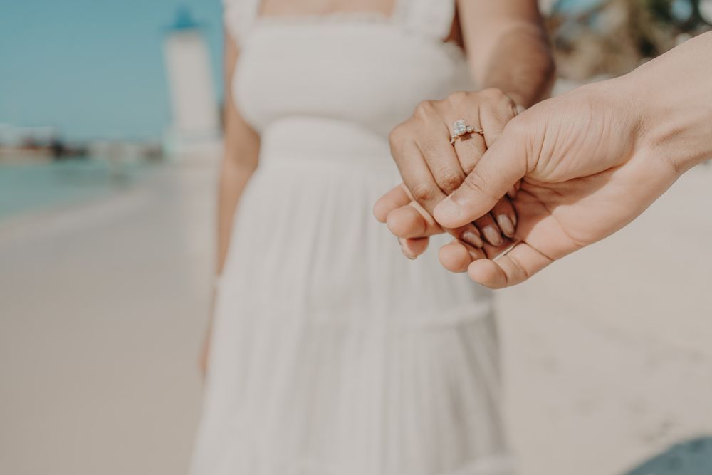Close-up of hands tenderly touching against a beachy backdrop photoshoot in Puerto Morelos.