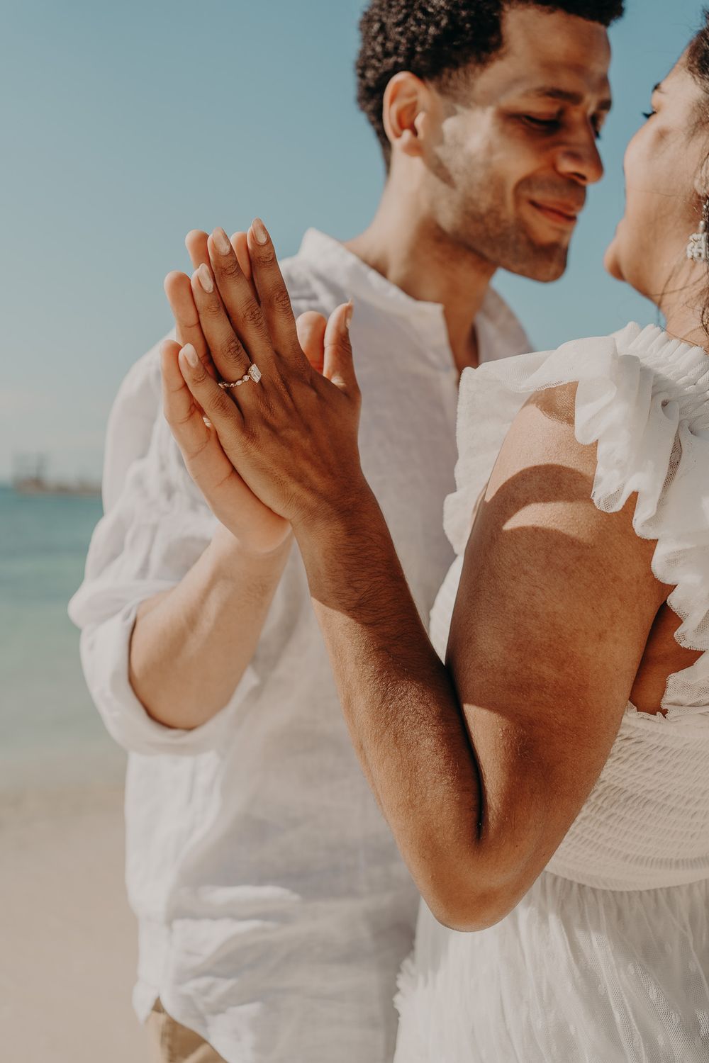 Intimate moment captured between couple in white attire on a tropical beach photoshoot in Puerto Morelos.