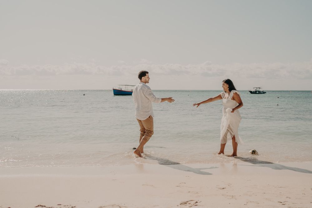 Couple playing and running together on a pristine white sand beach photoshoot in Puerto Morelos.