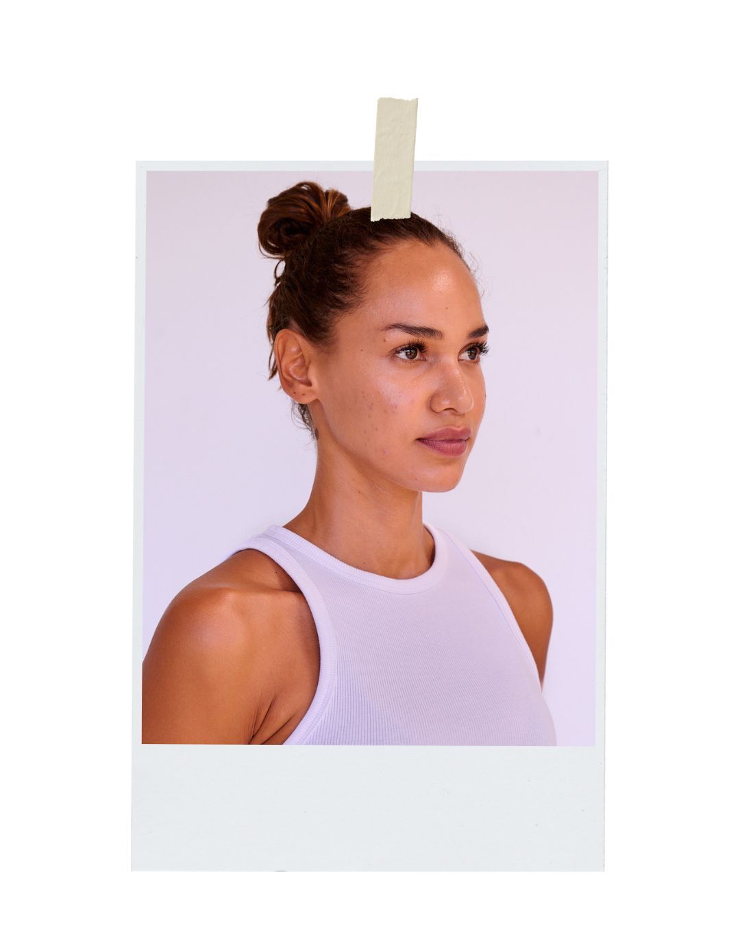 Portrait of an athletic person with a hair bun wearing a white sleeveless top against a pale background.