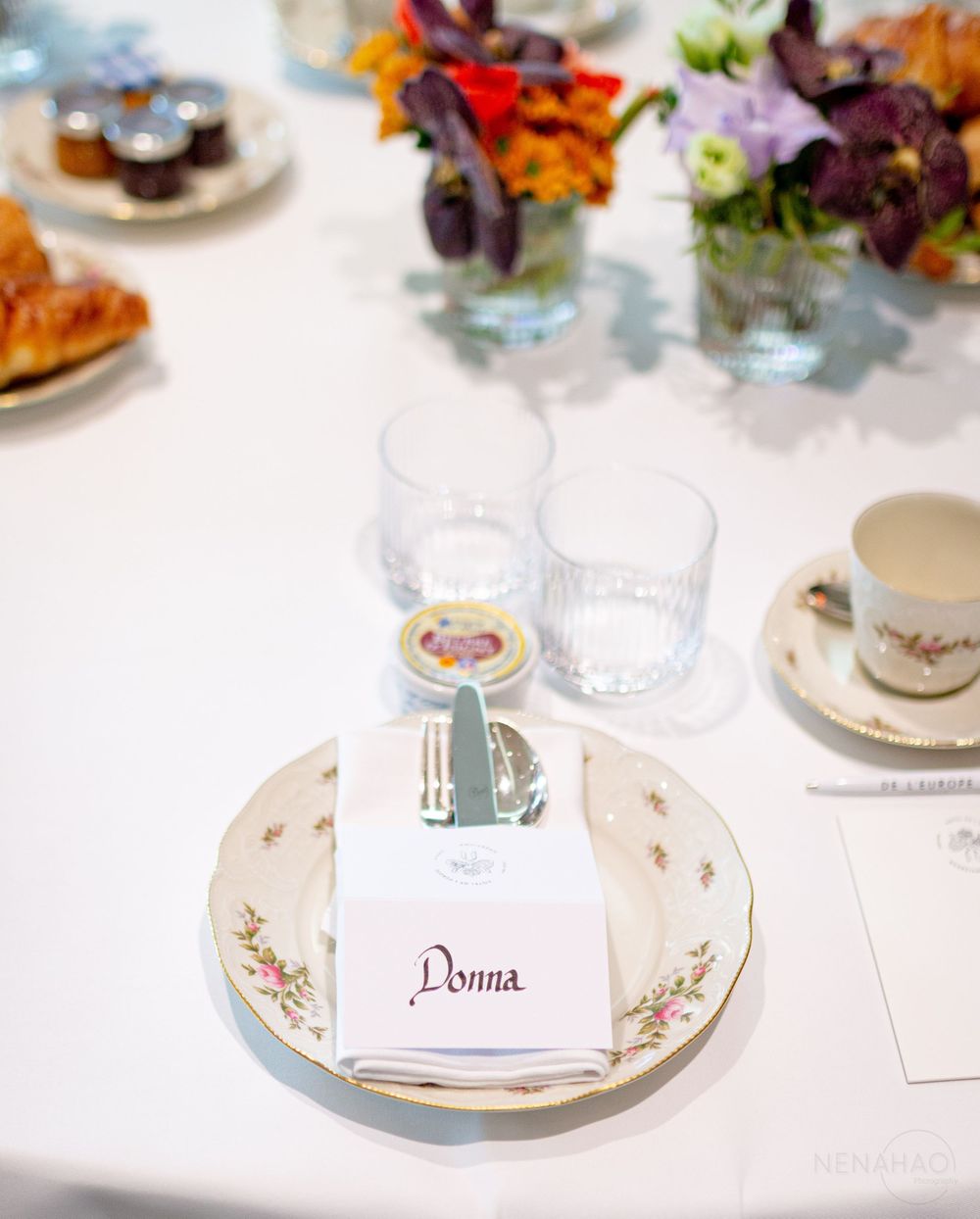 Place settings with decorative plates and name cards on a white tablecloth.