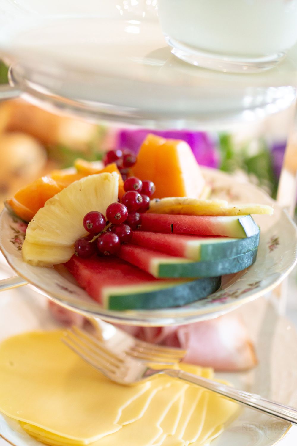 Fresh fruit plate with pineapple, watermelon, and red currants served on decorative china.