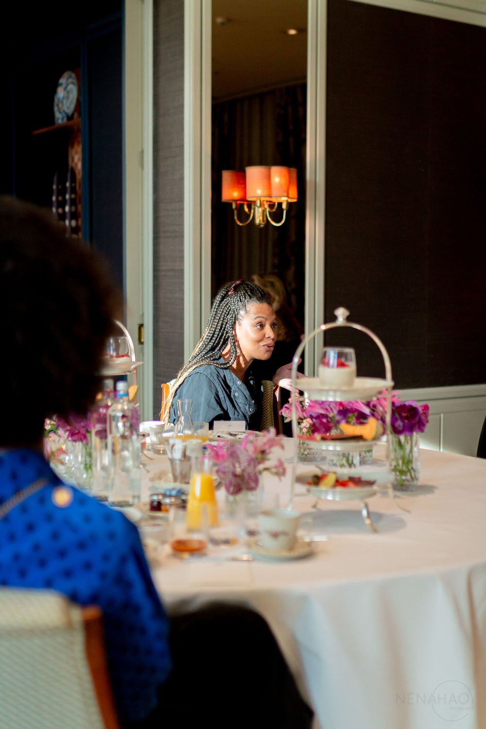 Elegant dining table setting with purple flowers and glassware in a sunlit room.