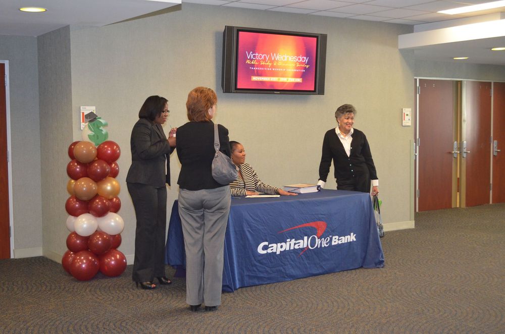 Capital One Bank representatives at a promotional table with balloon column display during a corporate event.