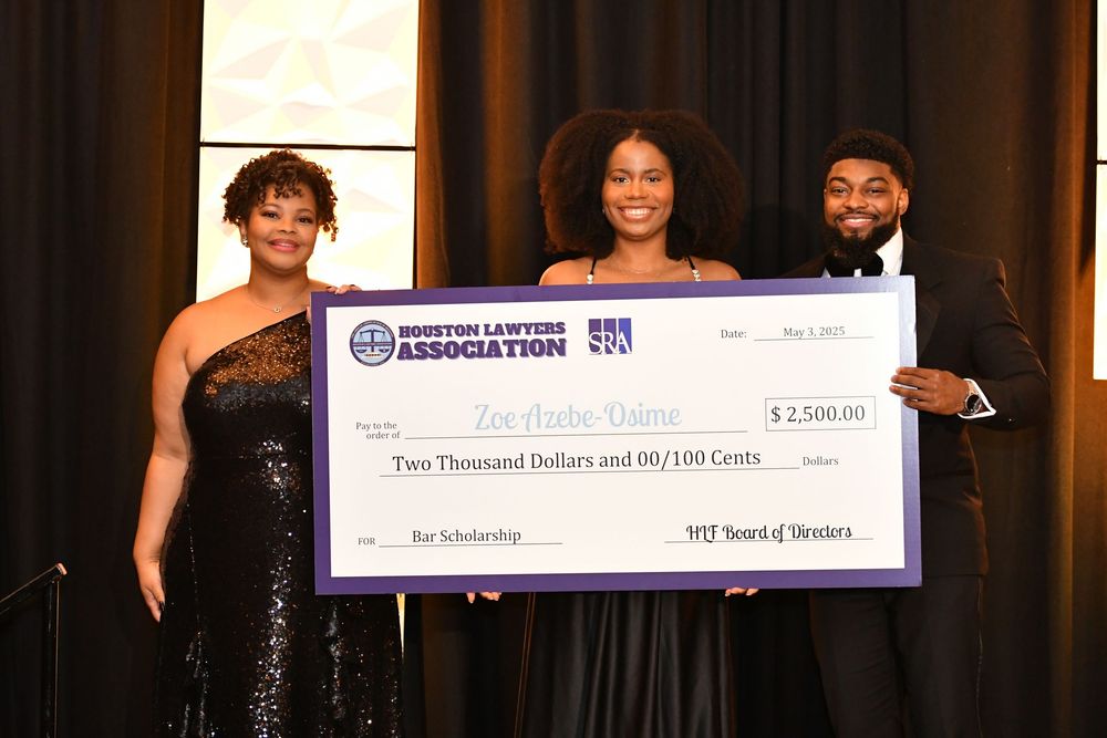 People pose with an oversized ceremonial scholarship check for $3,000 from United League of Brokers at an awards event.