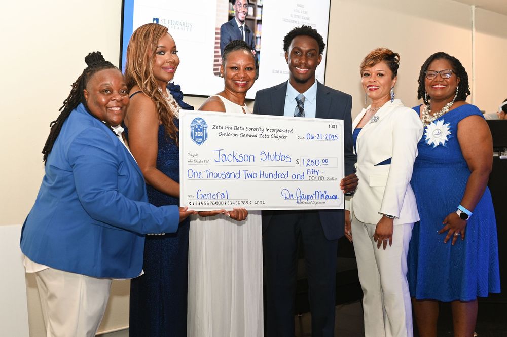 People in formal attire gather for a group photo wearing blue and white outfits at a social event.