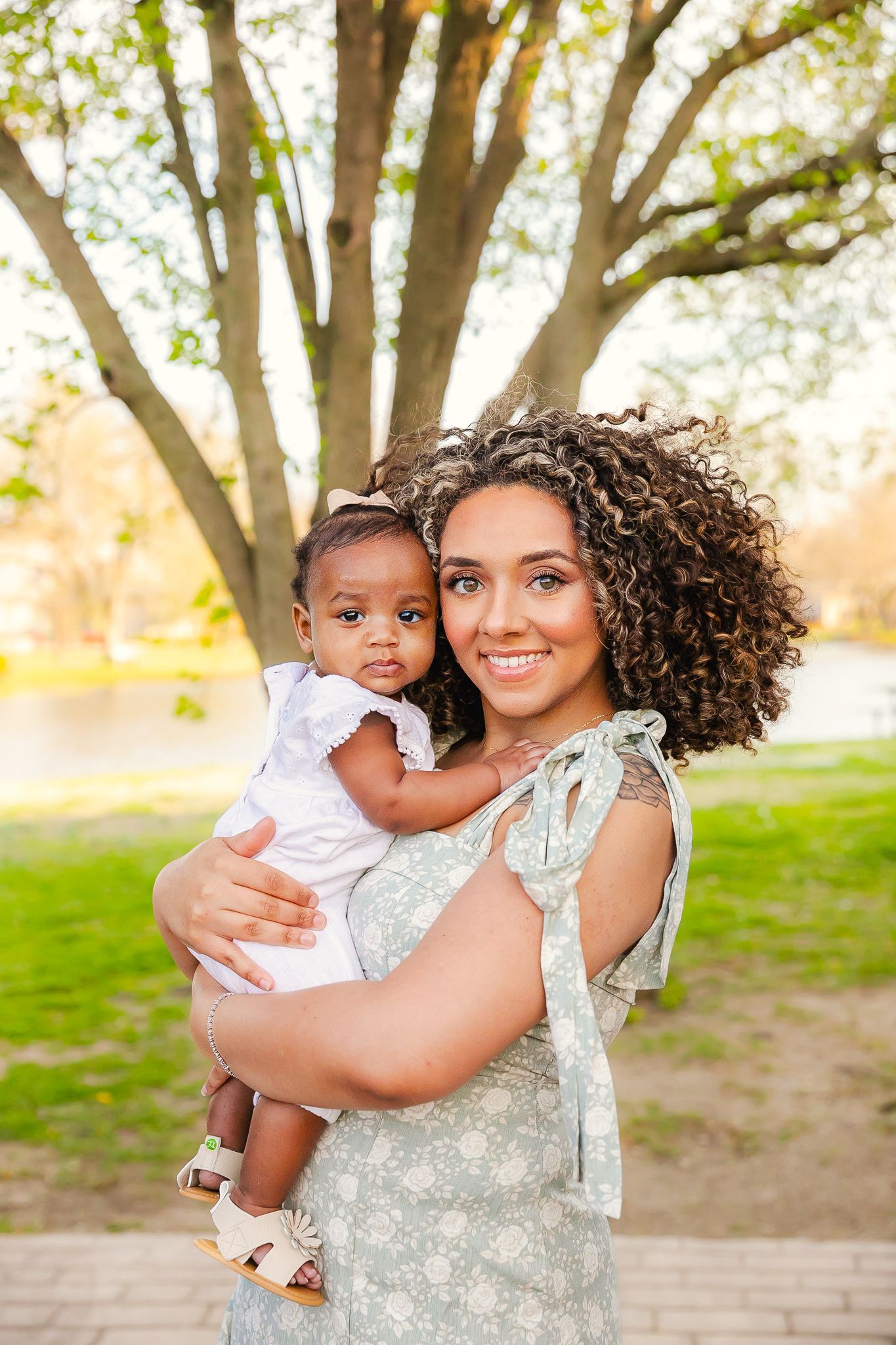 Beautiful portrait in a park with sunlit trees and a grassy landscape on a warm spring day for a lovely mom and daughter spring photoshoot.