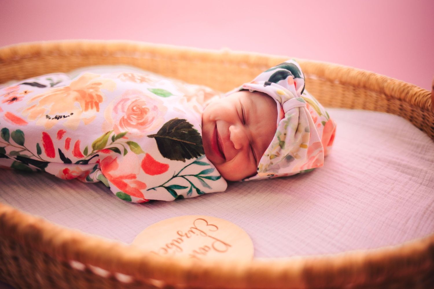 Smily swaddled baby on pink background in studio based in The Village
