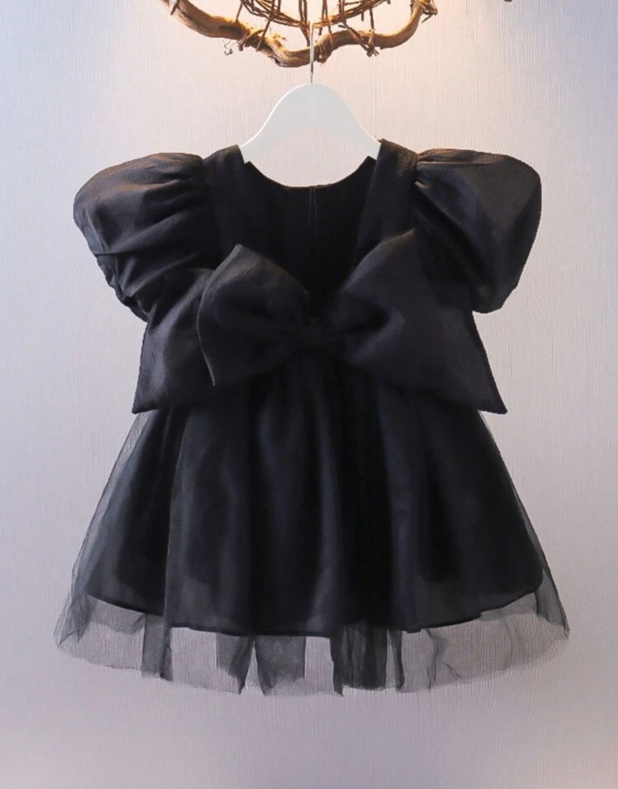 Black tulle dress with ruffled top displayed against white background.