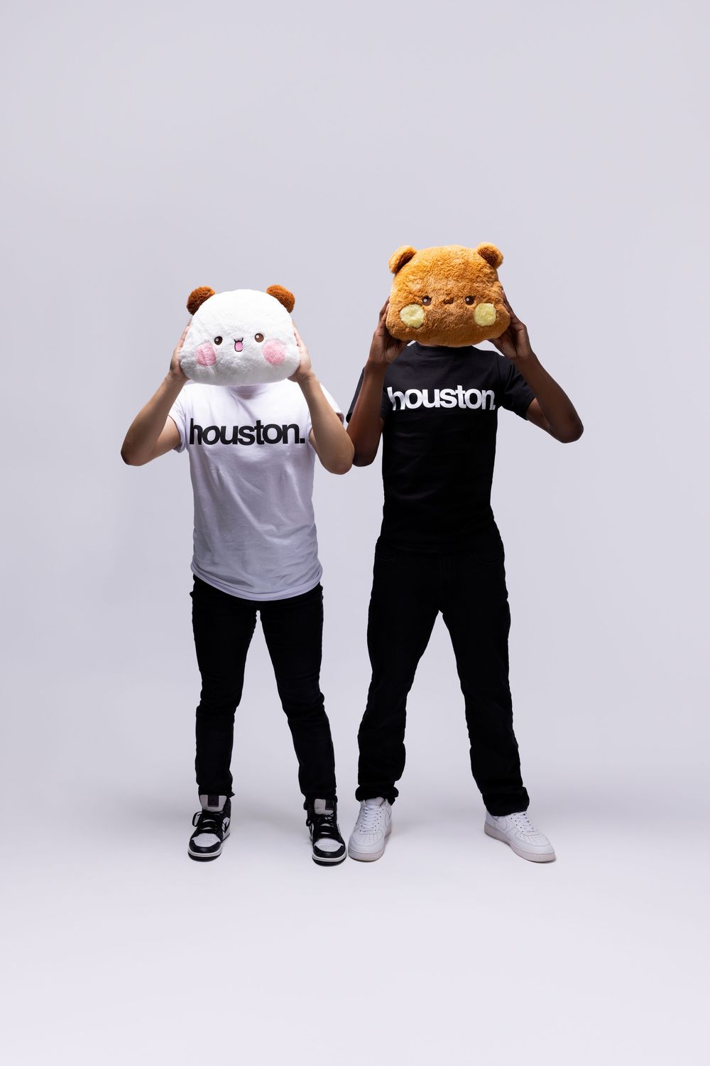 Two people wearing giant plush animal heads and Houston t-shirts in white and black pose against a light gray background.