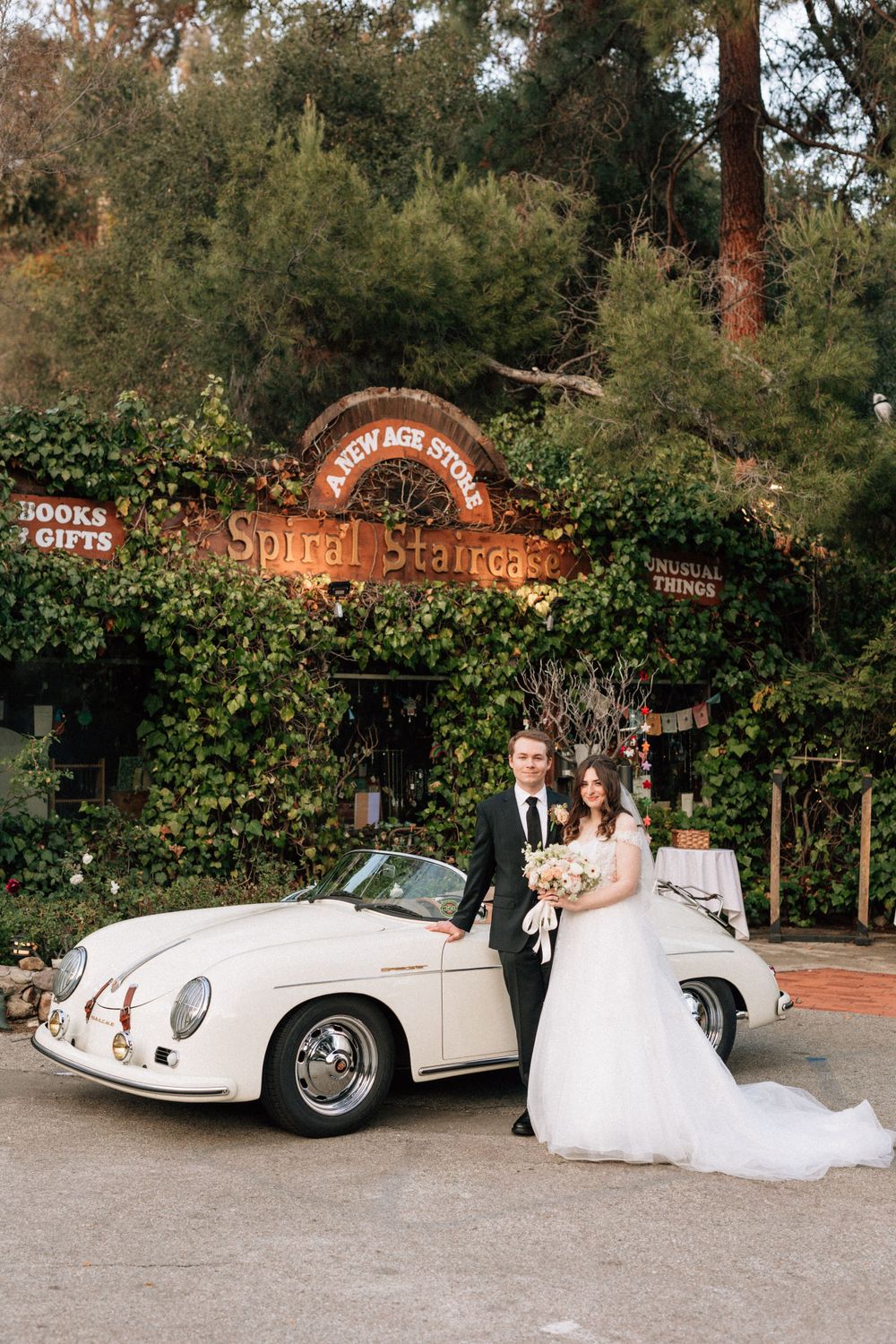 A bride and groom kiss in front of a vintage car for wedding photography in topanga canyon