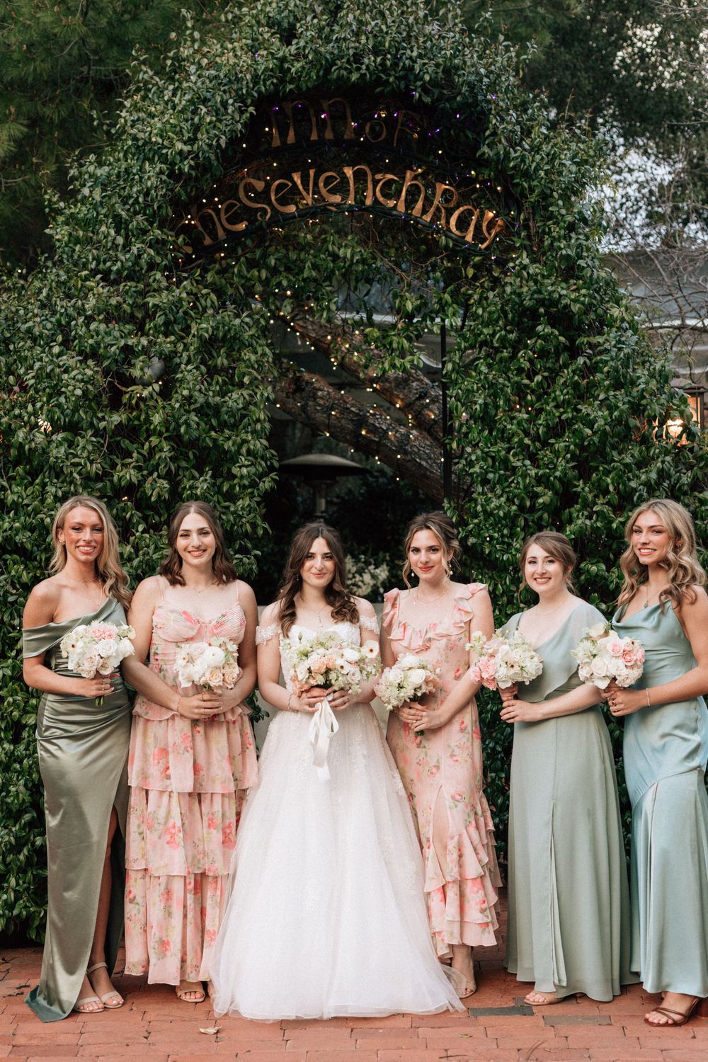 a bride and her bridesmaids stand together with inn of the seventh ray sign