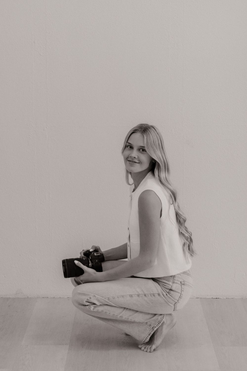 A minimalist black and white photo series showing a person in white clothing sitting and reclining against a plain wall.
