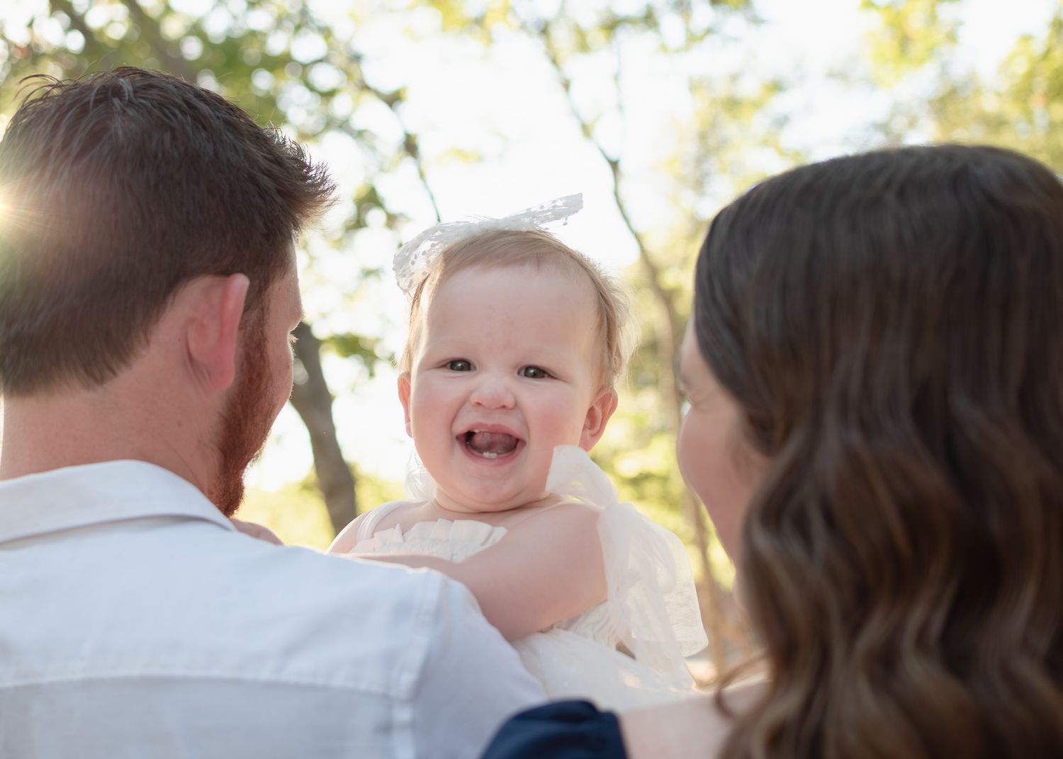 Parents holding smiling baby during a golden hour session with a Belton Texas family photographer