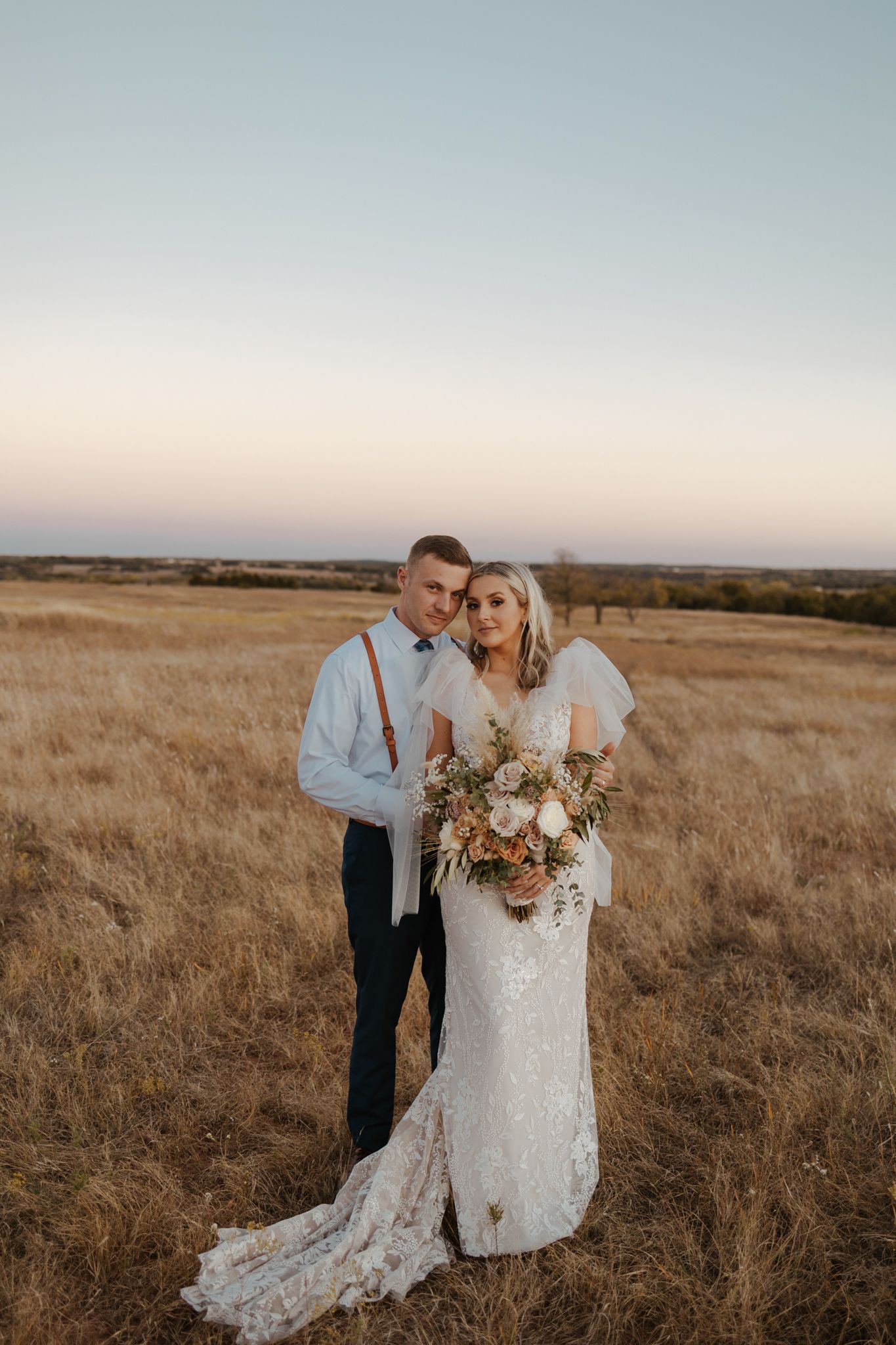 A romantic sunset portrait in a golden field with a bouquet of autumn-colored flowers.