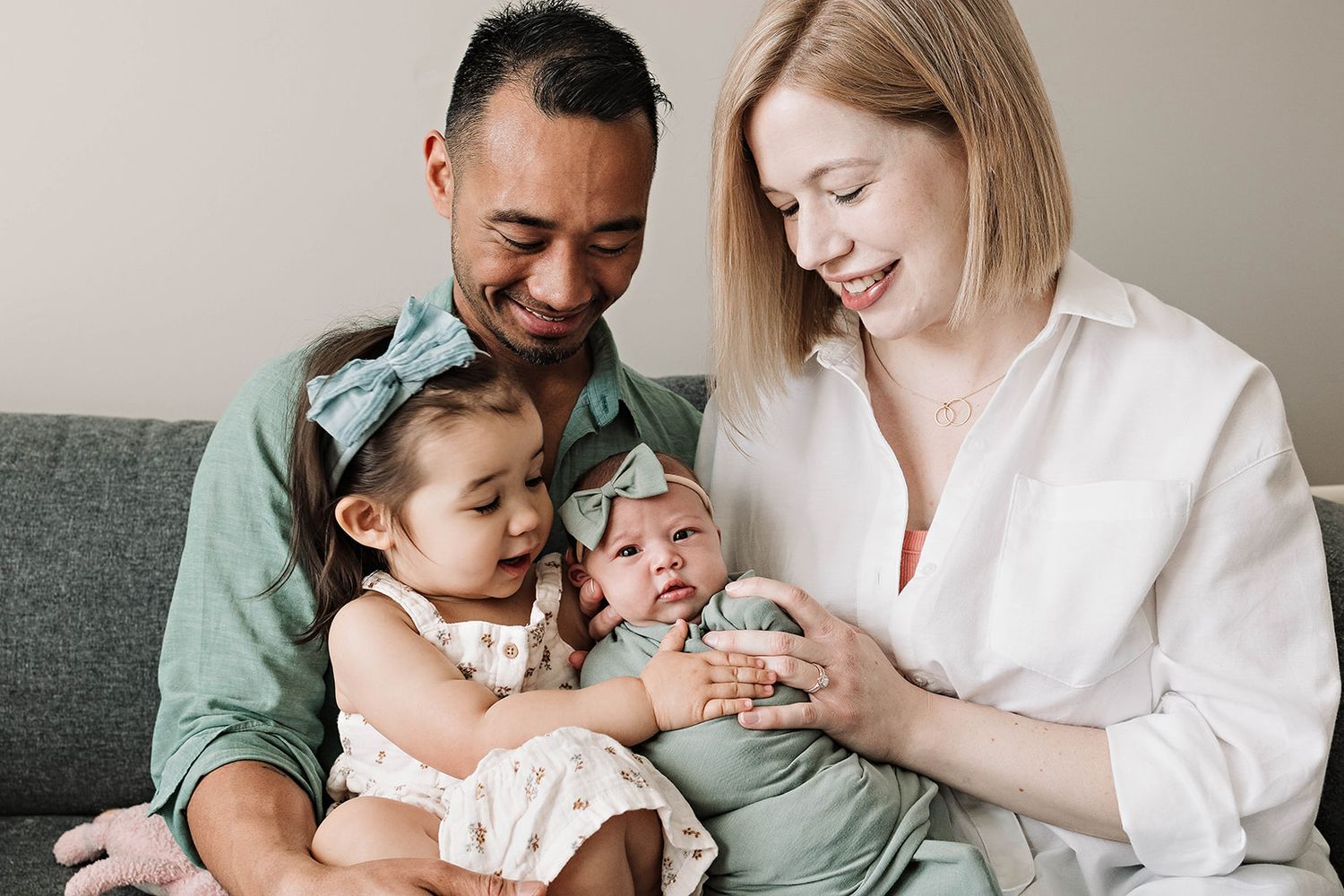 A photo with a lifestyle view of heartwarming family moment showing parents, a toddler girl and a newborn cuddling at home near Fallston MD