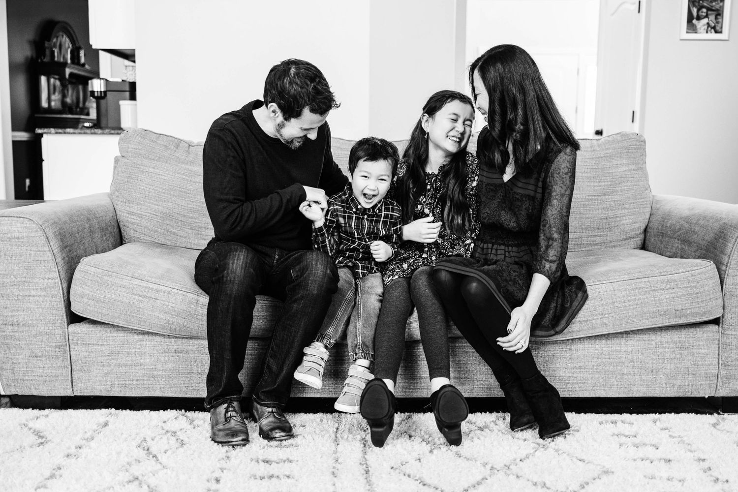 A black and white photo of a family sitting together on a couch sharing a lifestyle of laughter and joy in their home near Fallston MD